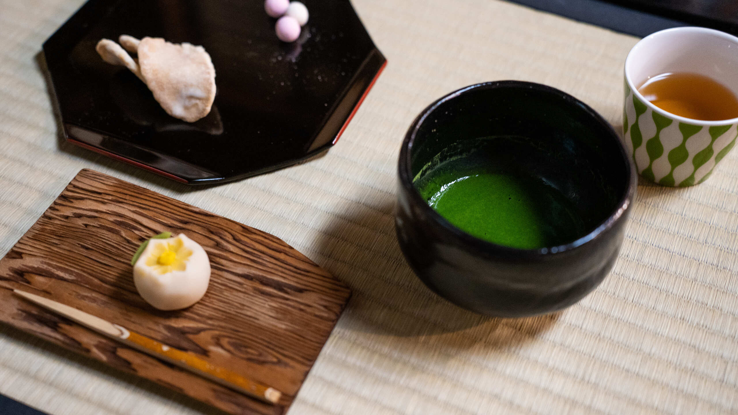 抹茶と主菓子と花が飾られている